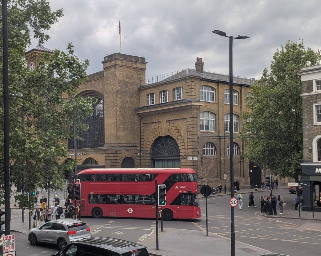 cloudy skies above Kings Cross St Pancras station in London with a red London bus entering Pentonville Rd. 
